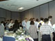 A mass of conference attendees enjoy both food and tabletop displays