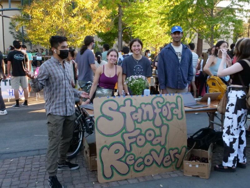 Students behind a table at a club fair with a Stanford Food Recovery sign