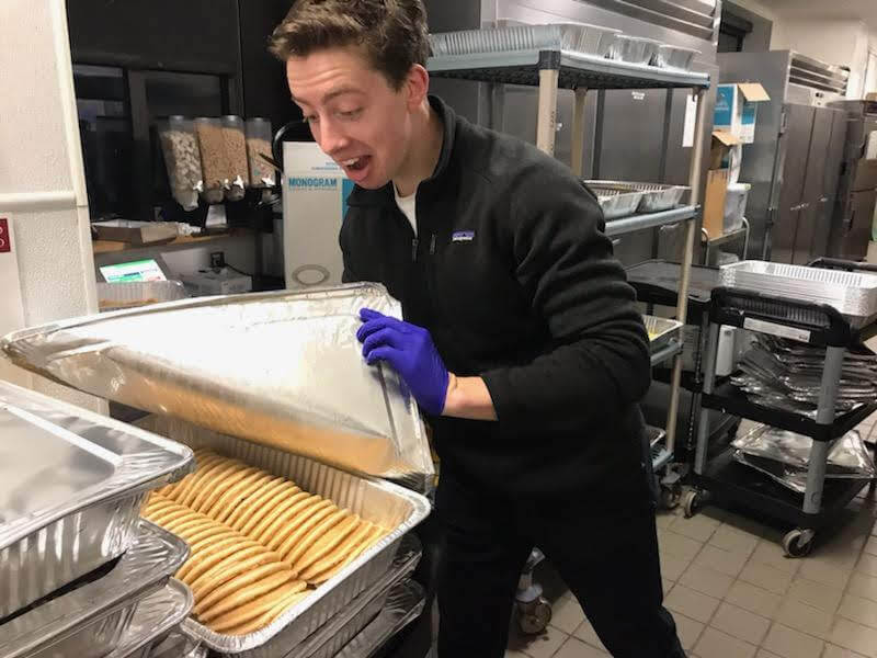 A student volunteer looking at a tin of recovered pancakes