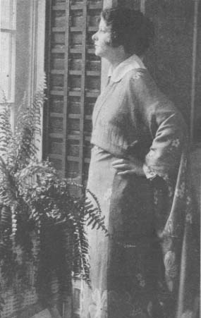 Norma Talmadge standing next to a window
