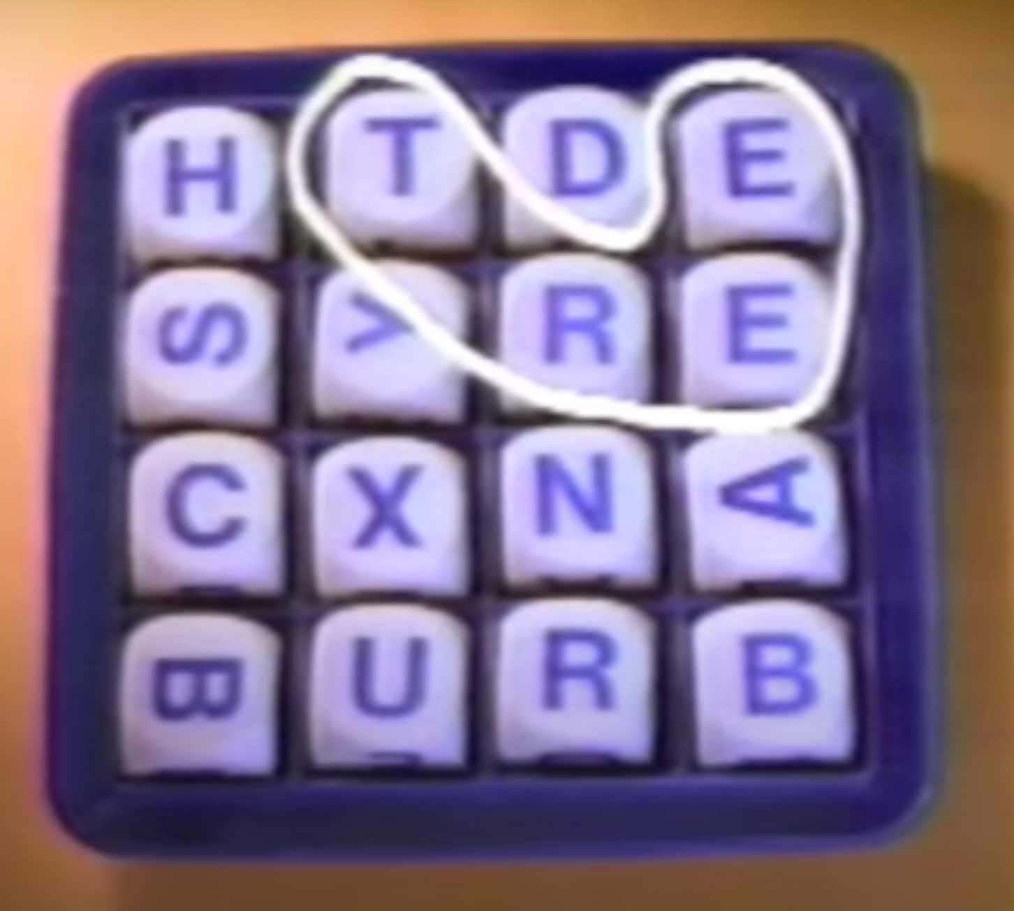 A Boggle board, with letters in a 4x4 grid. The letters in the first row of the image are 'H T D E', the second row has 'S Y R E', the third row has 'C X N A', and the fourth row has 'B U R B'