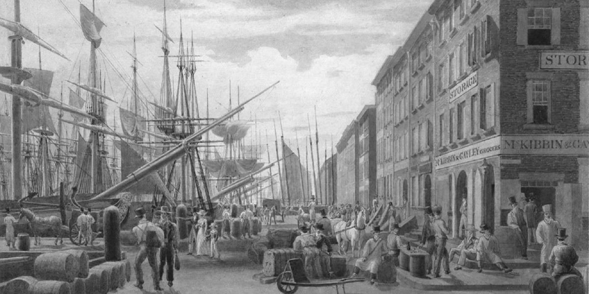 This watercolor painting by William James Bennett shows a busy port station in New York City in 1827. The left side of the painting depicts a row of merchant ships docked in a harbor. People line the foreground of the painting from left to right, many engaged in conversation with others, some are standing near horse draw carriages, some are sitting on barrels of hay, some are sitting on the street corners, some lean and sit on wooden barrels, some are walking into merchant shops, and one family standing to the center left of the scene points to the docked ships.