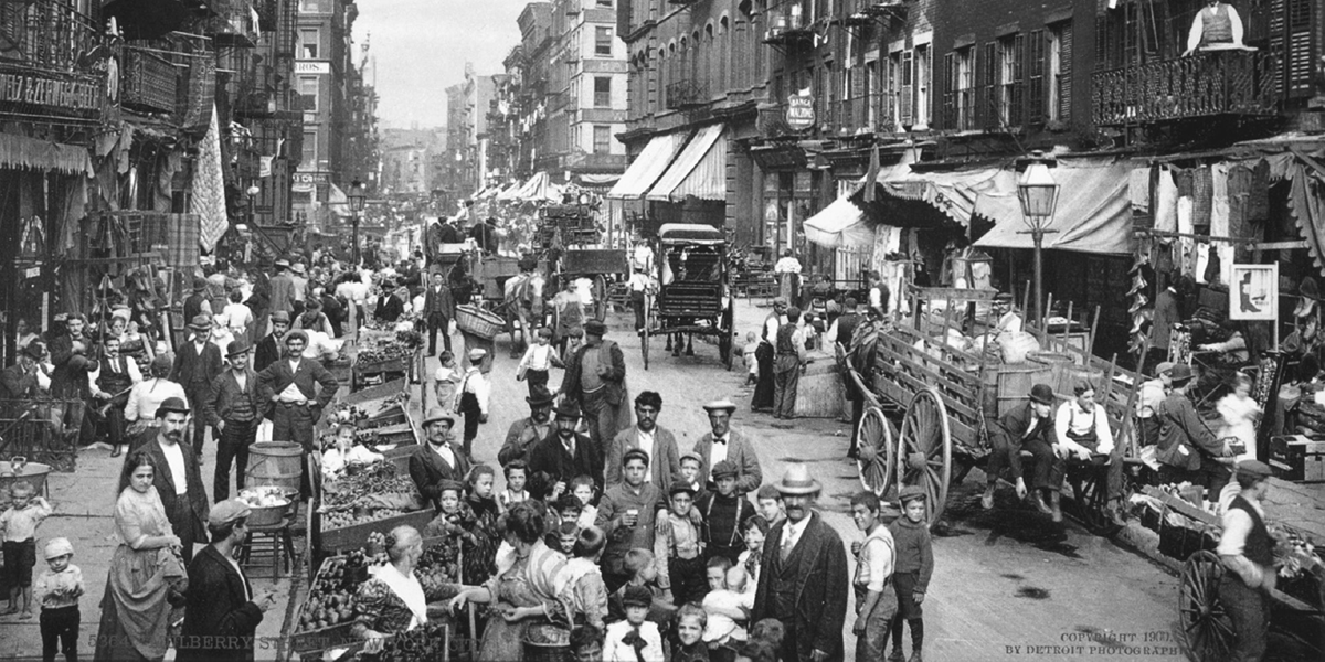 A busy urban street filled with stalls, wagons, and pedestrians.