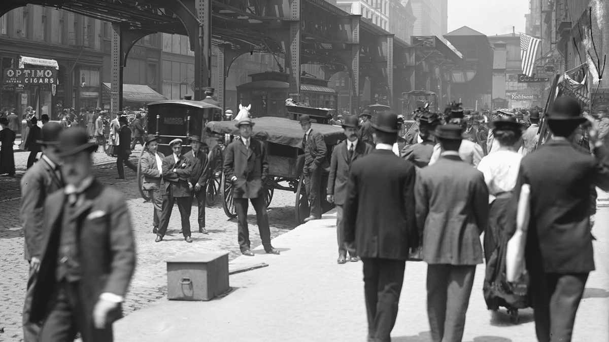 A crowded urban street scene in front of an elevated railway.