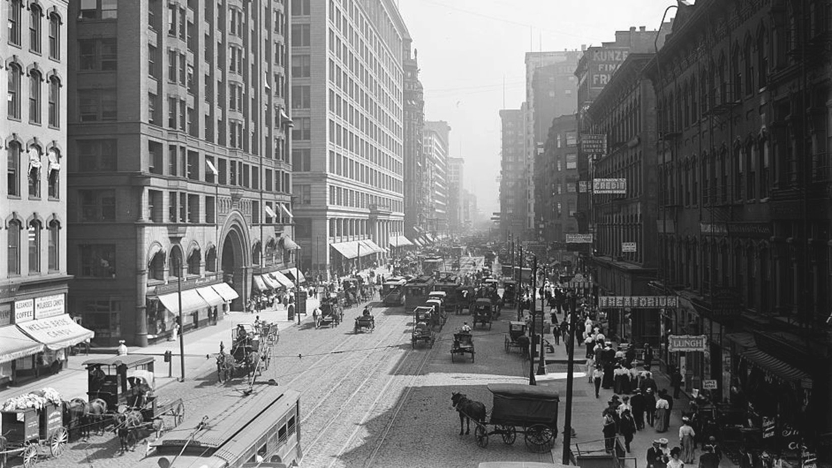 A wide, crowded street amid skyscrapers.
