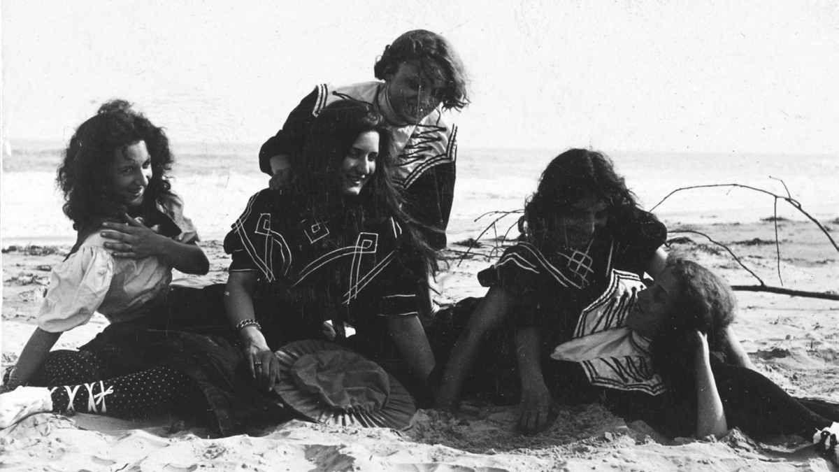 A group of women pose on a beach.