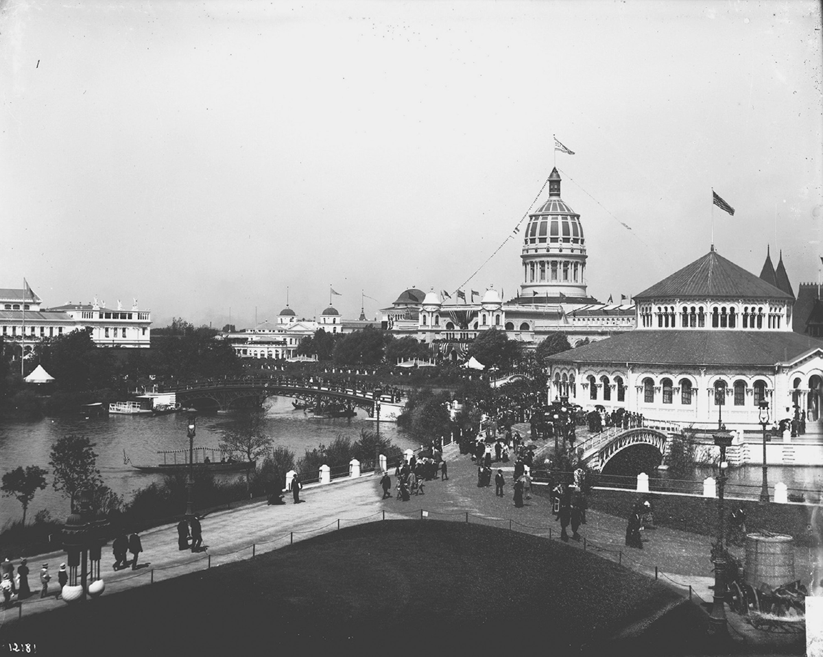 Visitors move through a pastoral scene of water, grassy knolls, and neoclassical buildings.