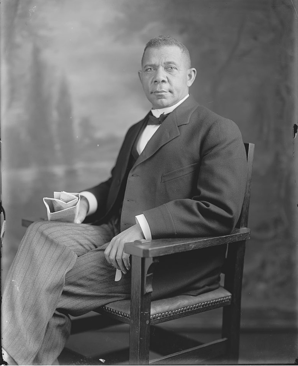 A man in a suit sits in a chair.