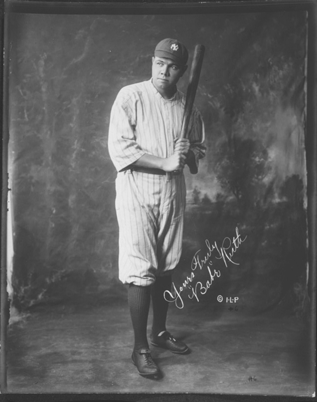 A man in a baseball uniform poses with a bat.