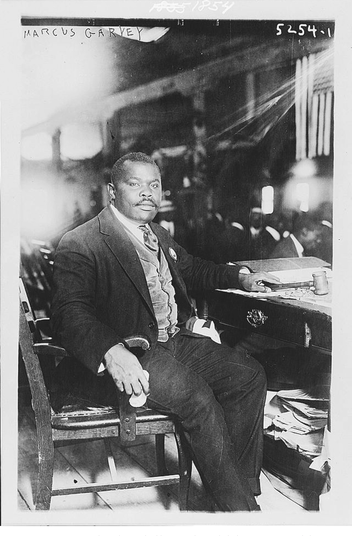 A man wearing a suit sits at a desk.