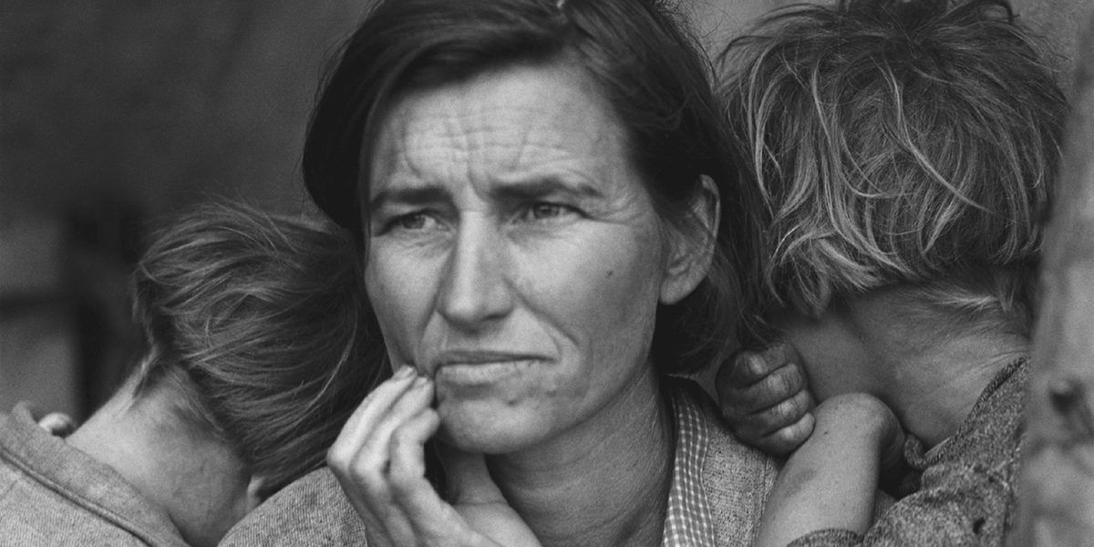 A woman looks worriedly into the distance, as two children rest against her shoulders.