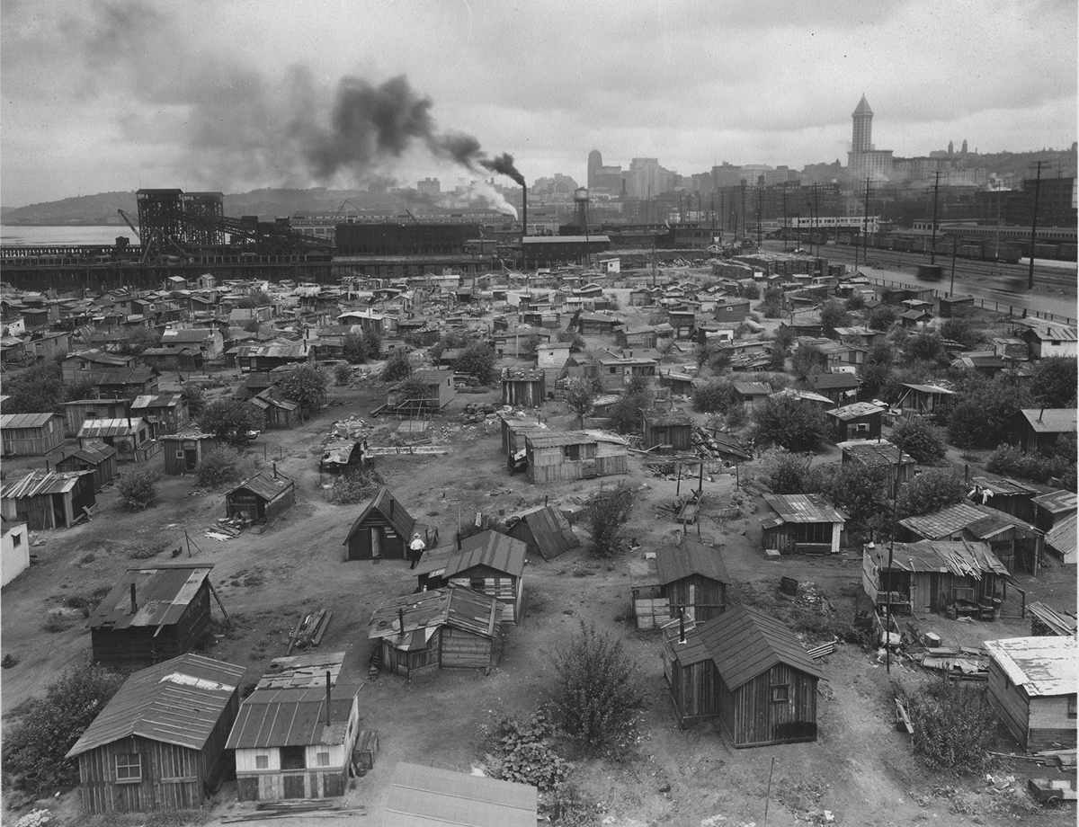 Shacks fill a large piece of land outside of a city.