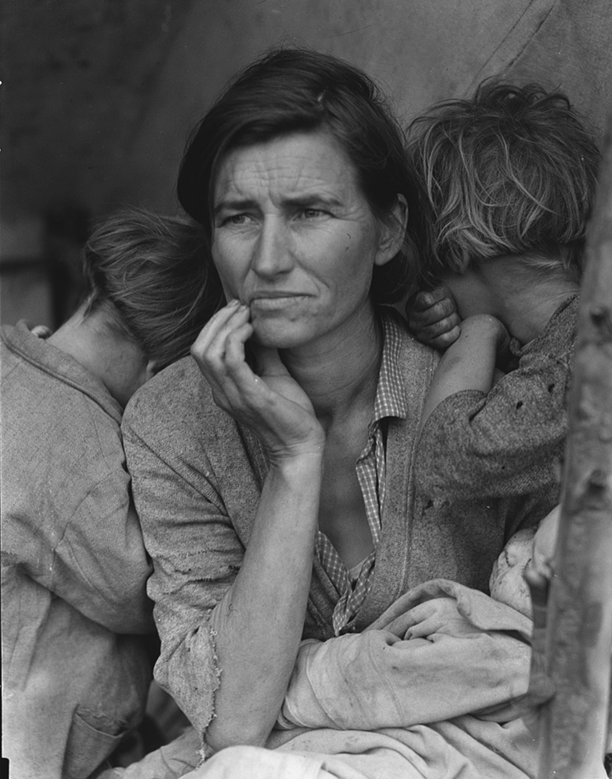 A woman looks worriedly into the distance, as two children rest against her shoulders.