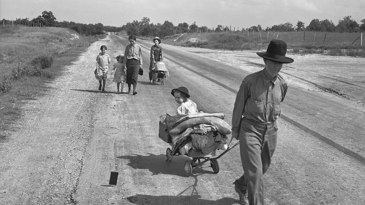 A family carries their belongings down a country road.