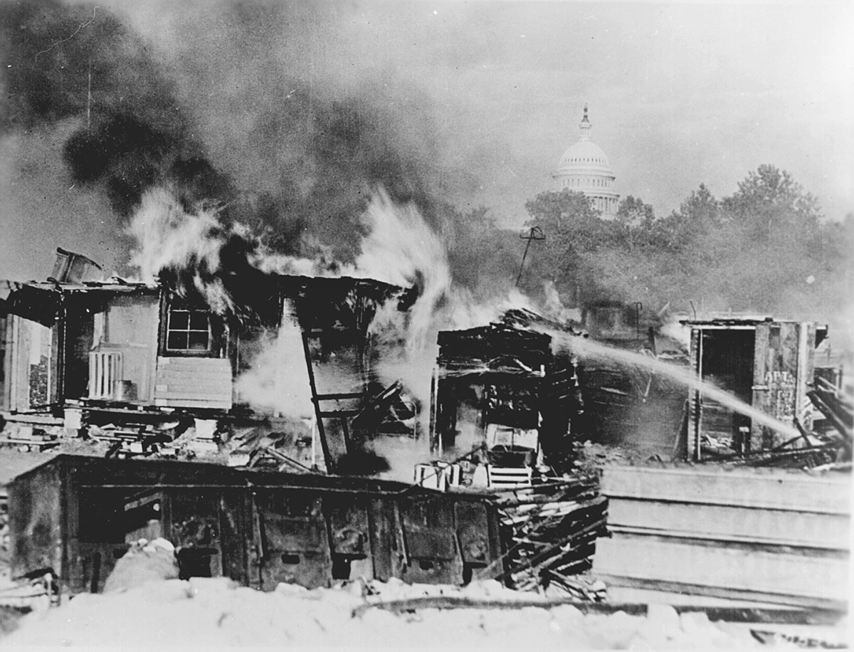 Shacks on fire with the US Capitol in the background.