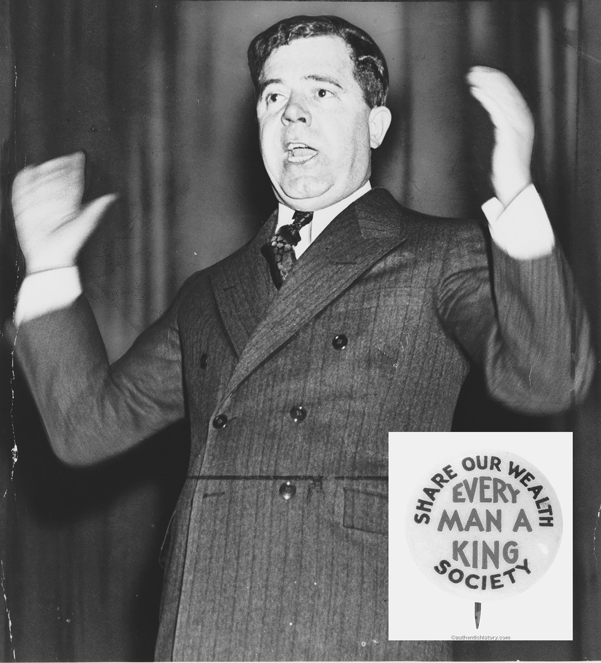 A man in a suit speaks with his arms raised.