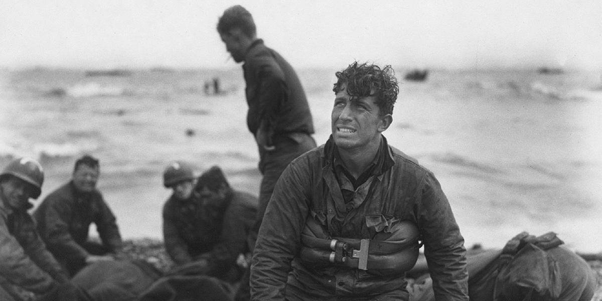 A soldier on a beach stares off camera.