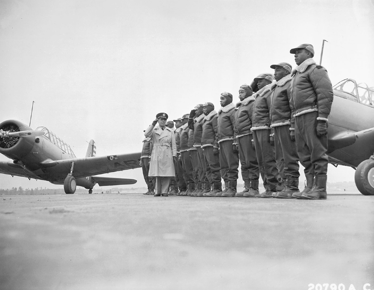 A row of airmen stand at attention before an officer.