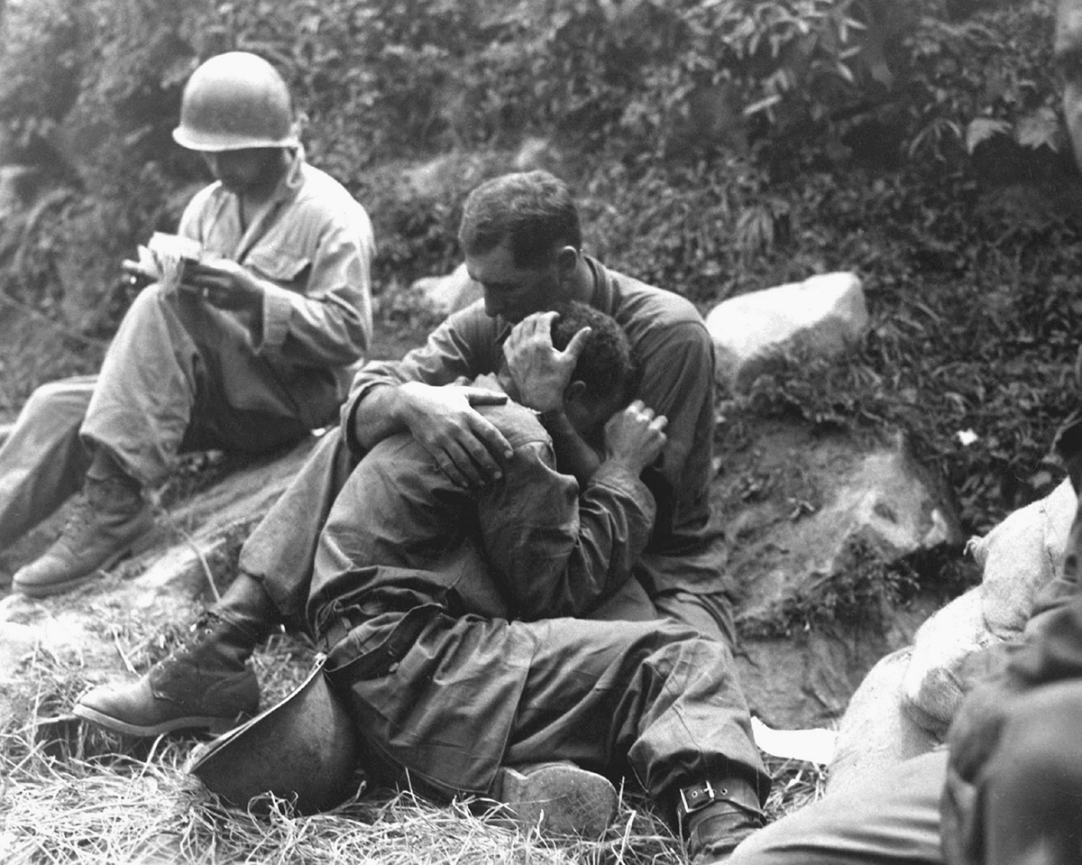 A soldier holds another soldier in his arms.