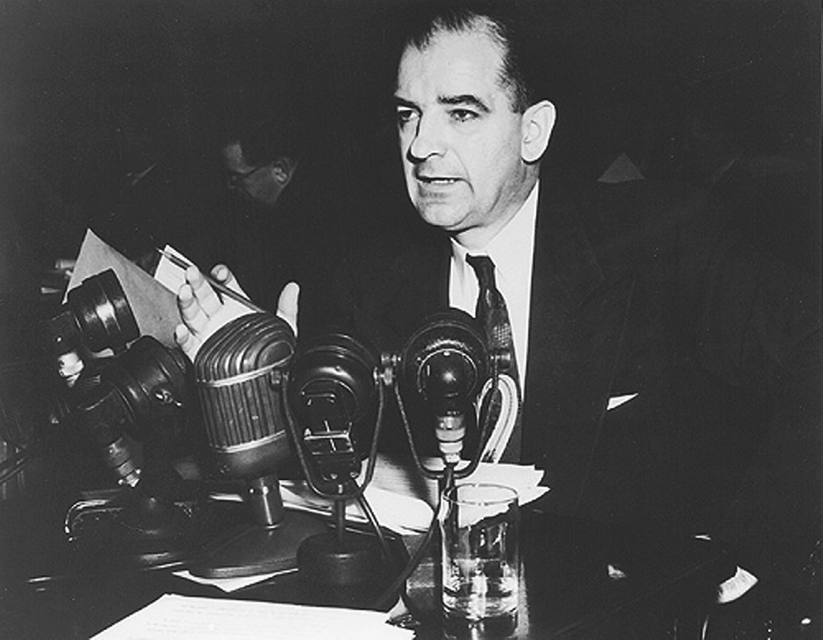 A man speaks in front of microphones.