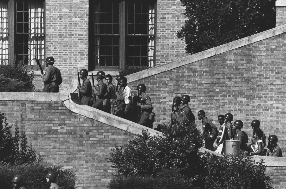 Soldiers escort students up the stairs of a high school.