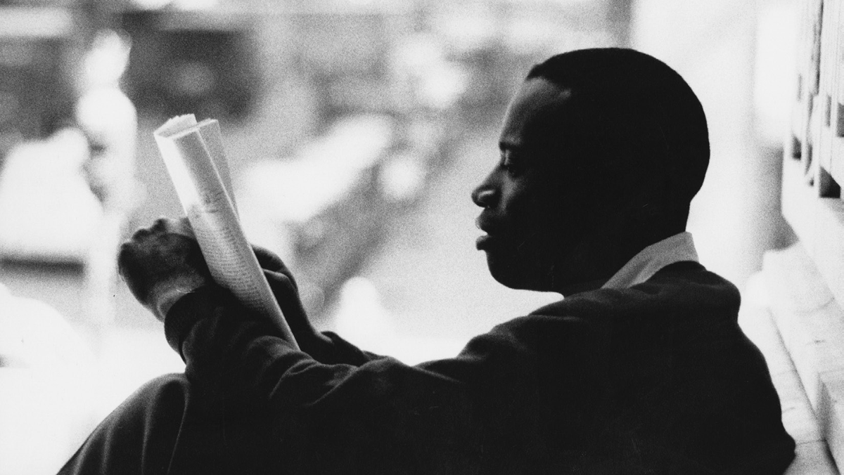 A young man reads a newspaper.