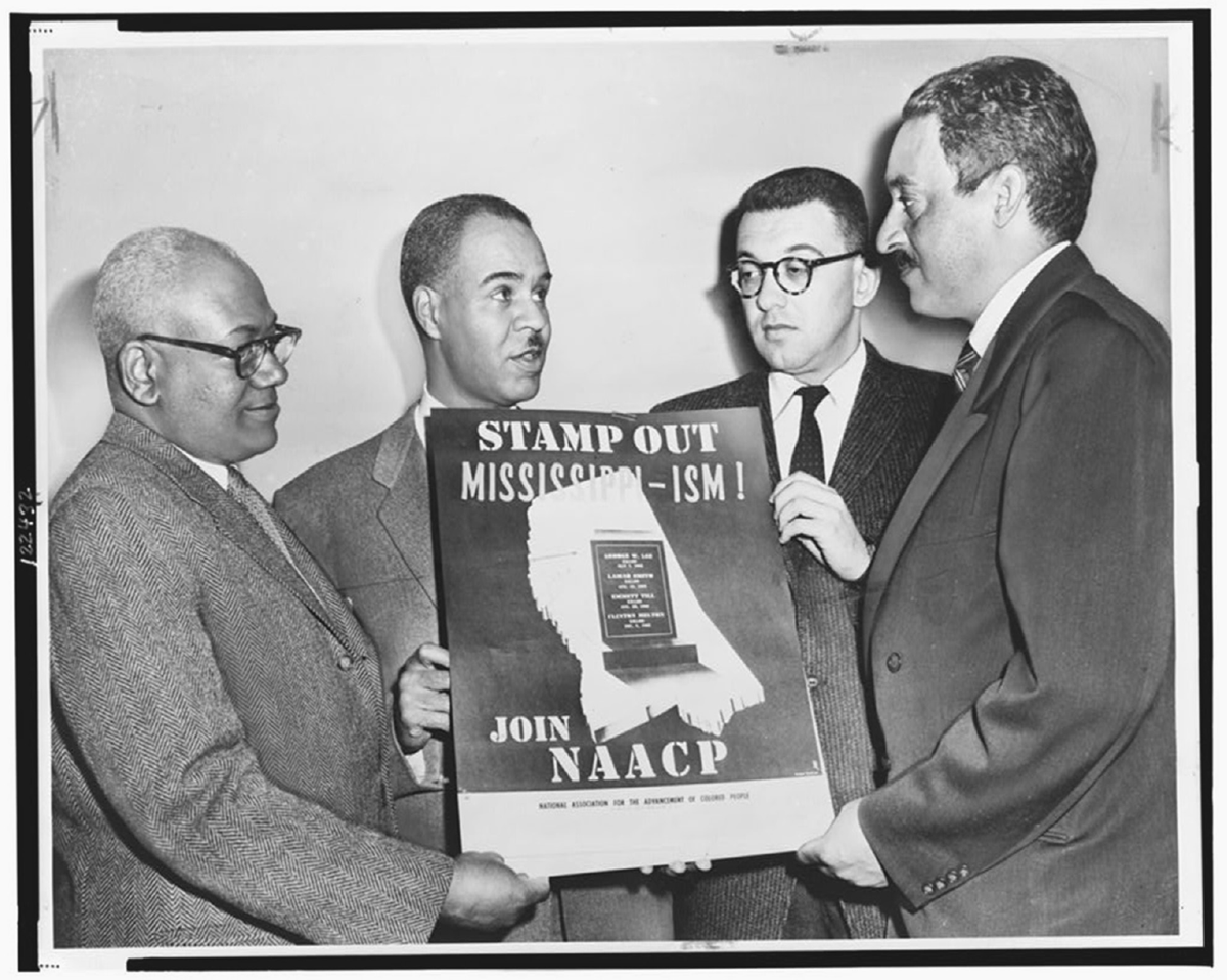 Four men hold a poster for the NAACP.