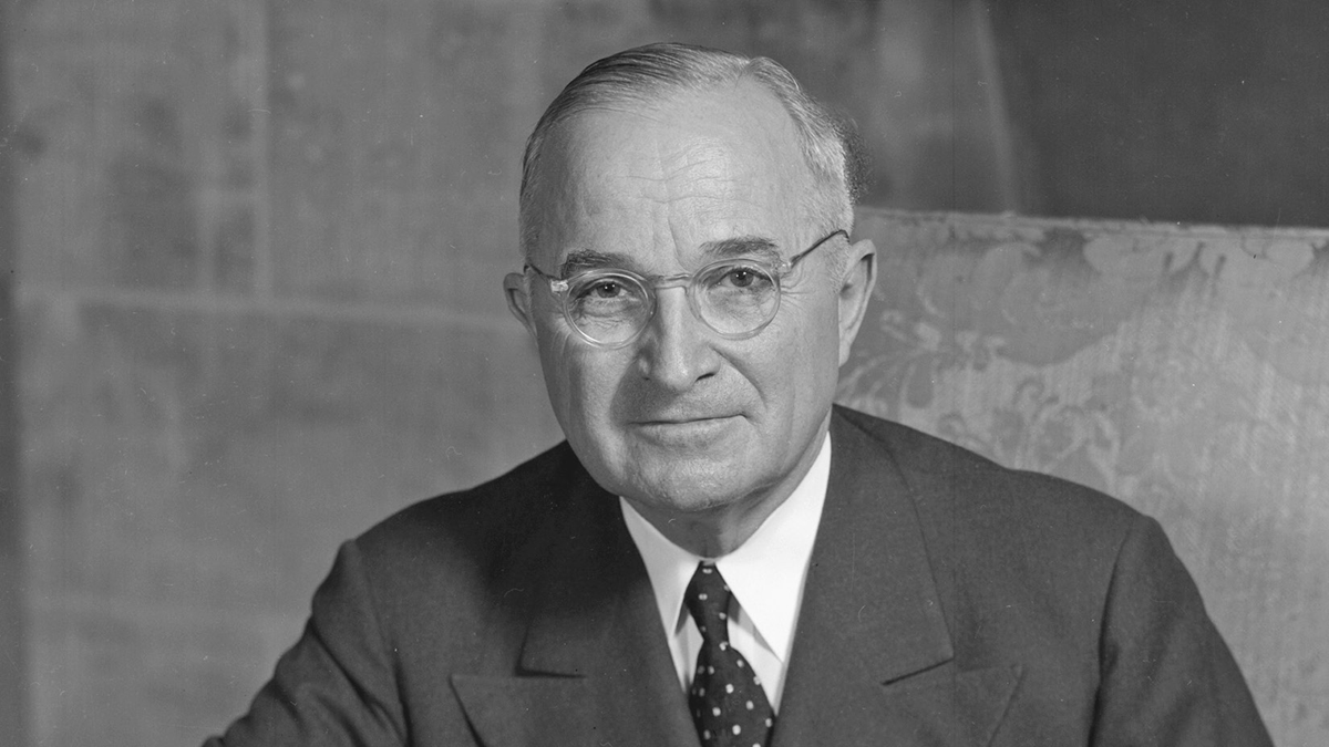 An older man holds a newspaper reading â€œDewey Defeats Truman.â€