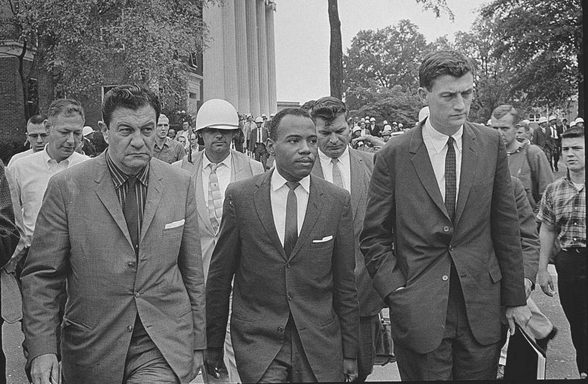 Three<noun? men?> move through a crowded scene.