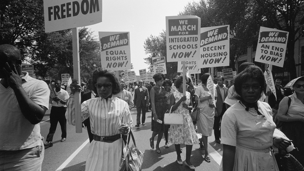 Men and women demonstrate. The placards advocate for equal rights and decent housing.