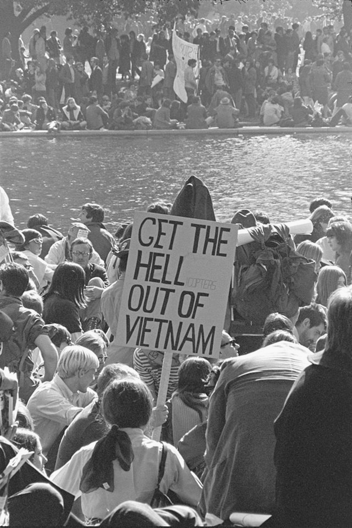 A crowd of protestors; one is holding a sign reading â€œGet the Hell Out of Vietnam.â€