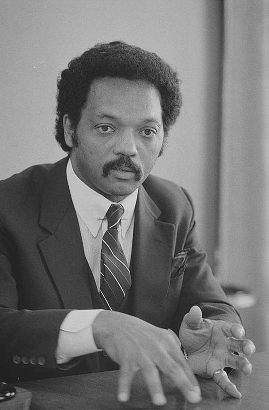 A man in a suit sits at a desk.