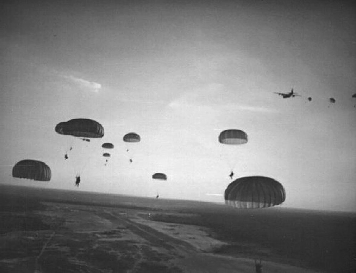 An aerial photograph of soldiers parachuting.