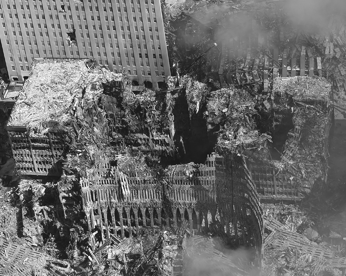 The husk of a devastated building stands amid wisps of smoke.