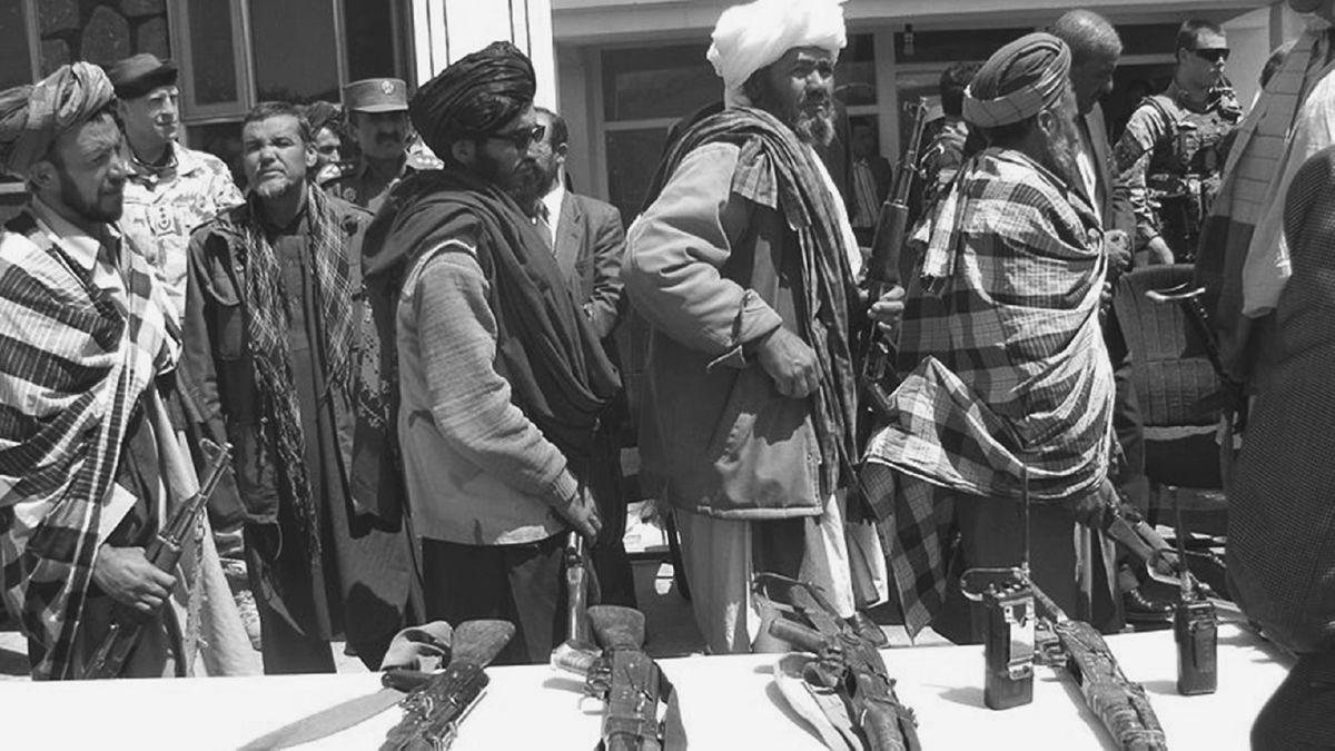 Taliban fighters place their rifles on a table.