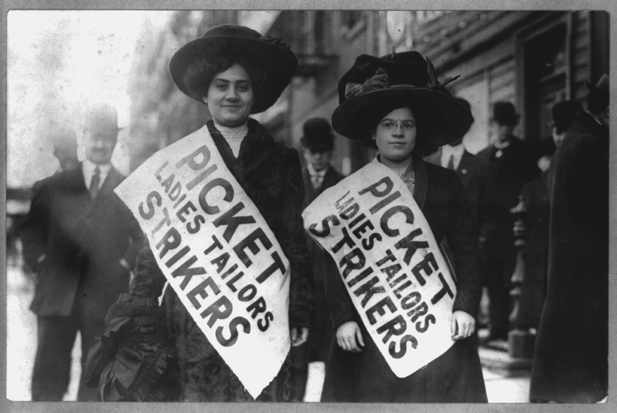 Two women strikers wearing bonnets pose with large sashes reading â€œPicket Ladies Tailors Strikers.â€