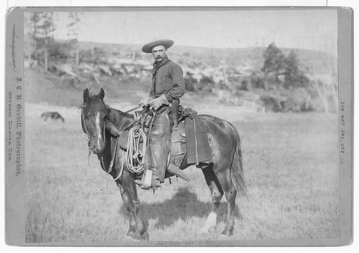 A cowboy poses atop a horse.