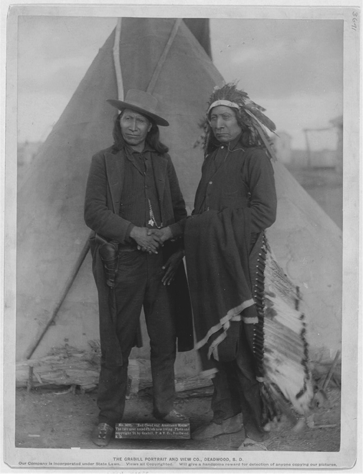 Two Indigenous men pose together shaking hands.