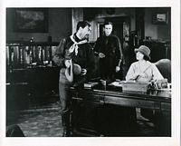 Frederick seated at desk with Eugene Pallette and Tom Santschi in western garb stand nearby